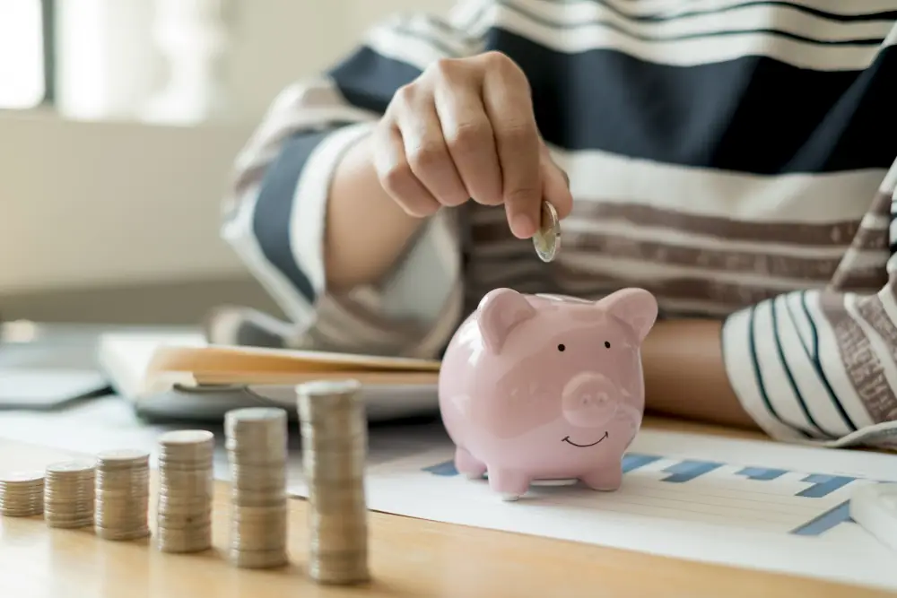 Someone putting coins into a piggy bank