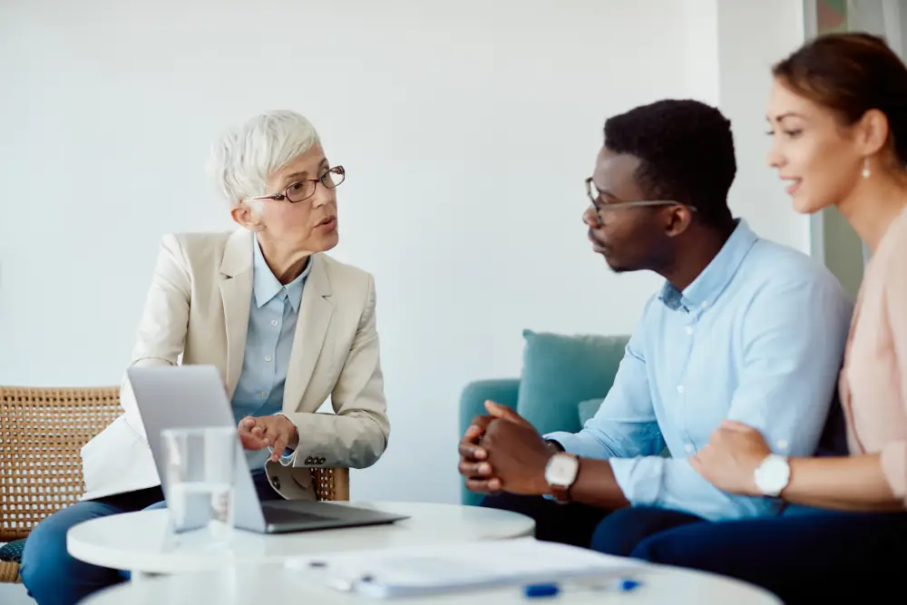 A professional showing 2 people something on a laptop