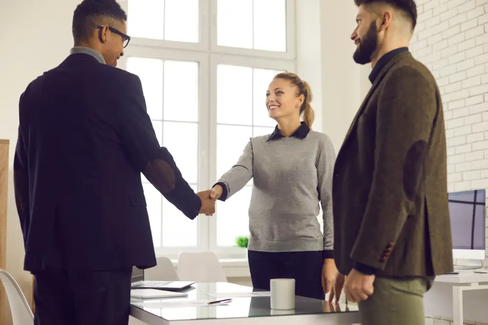 3 professionals shaking hands and smiling